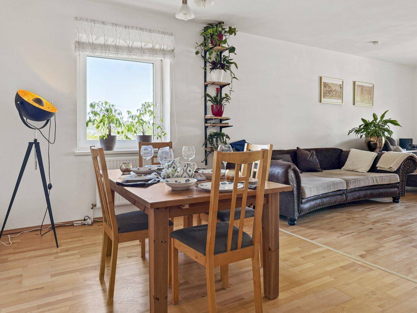 Offener Wohn- und Essbereich mit Holzboden, Esstisch und bequemer Couch.