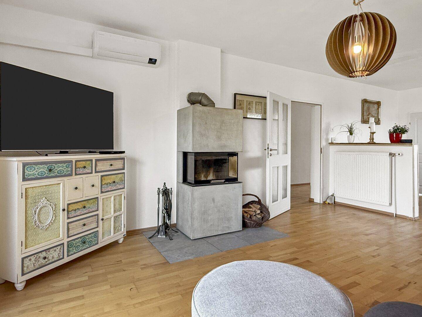 Heller Wohnbereich mit modernem Kamin, Fernseher und Klimaanlage.