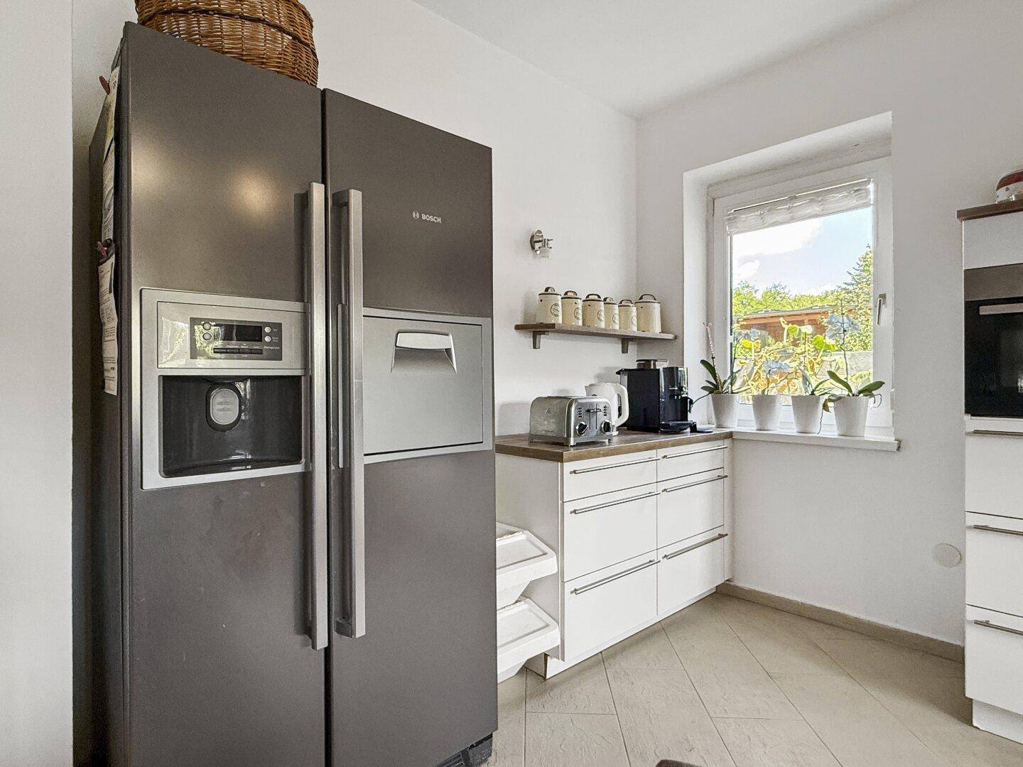 Großer amerikanischer Kühlschrank von Bosch in einer hellen Küche mit Fenster.