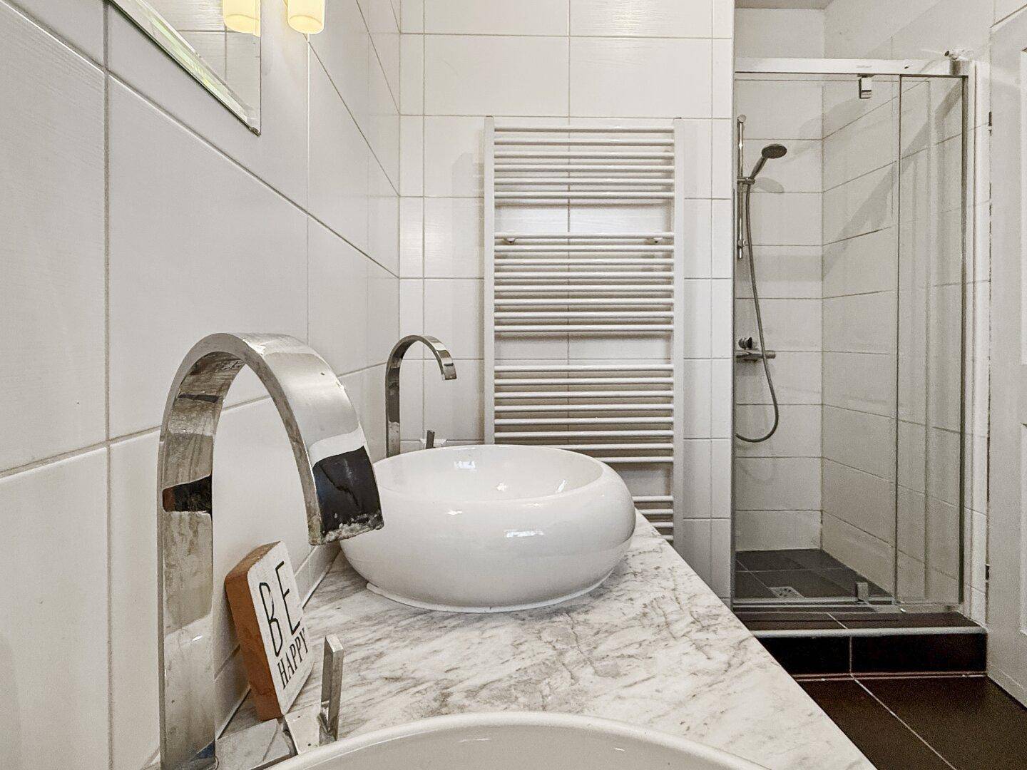 Badezimmer mit begehbarer Dusche, beheiztem Handtuchhalter und zwei Waschbecken.