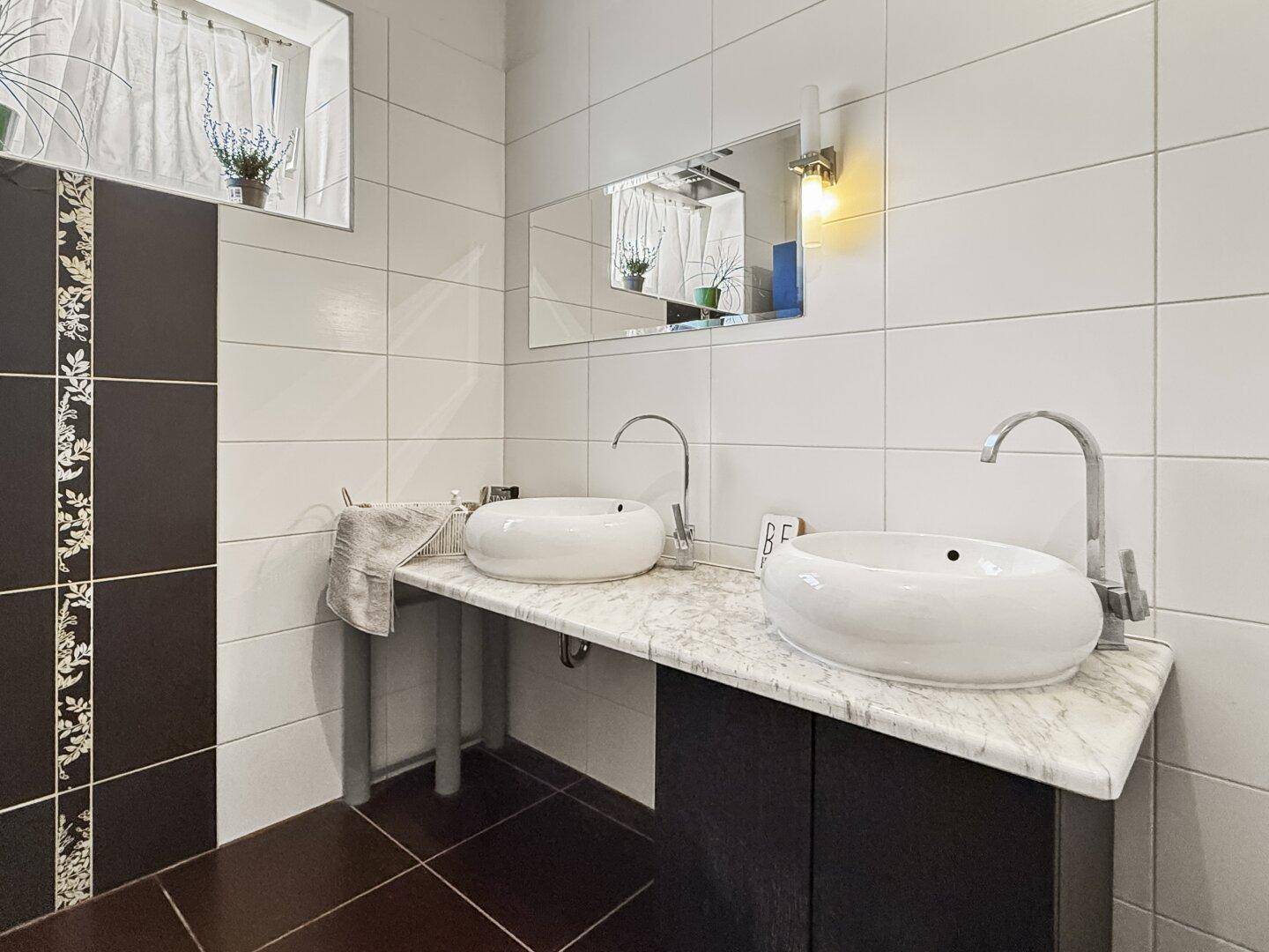 Modernes Badezimmer mit zwei Aufsatzwaschbecken und weißen Fliesen.