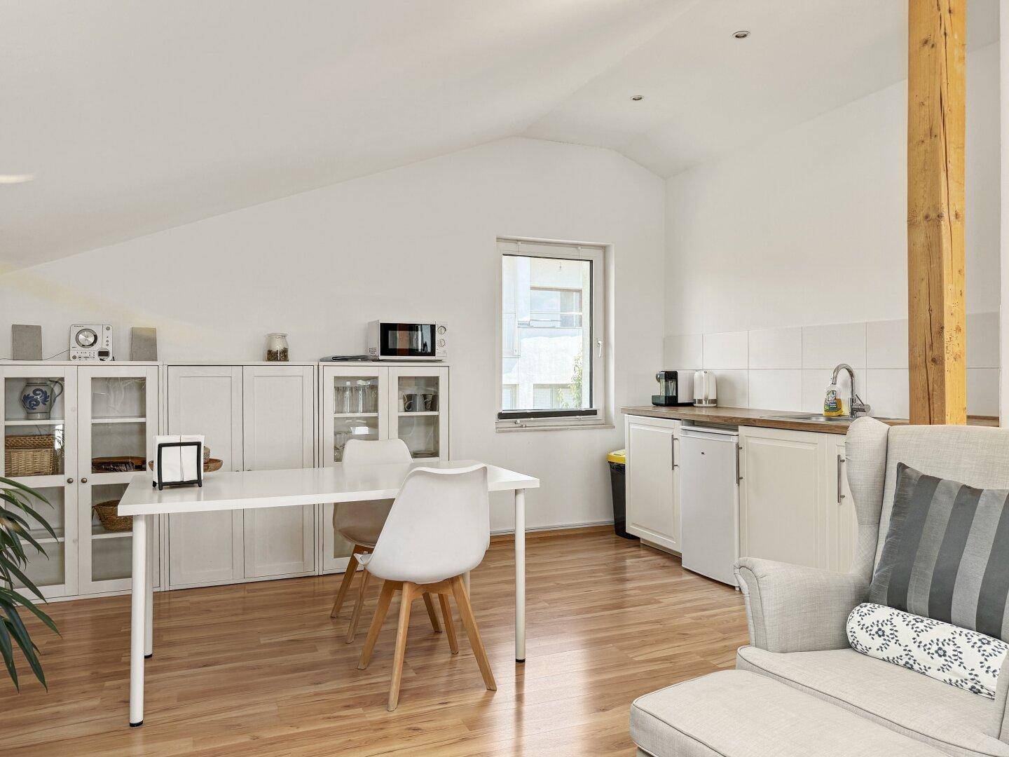 Kleine Küchenzeile im offenen Wohnbereich mit Spüle, Kühlschrank und Esstisch.