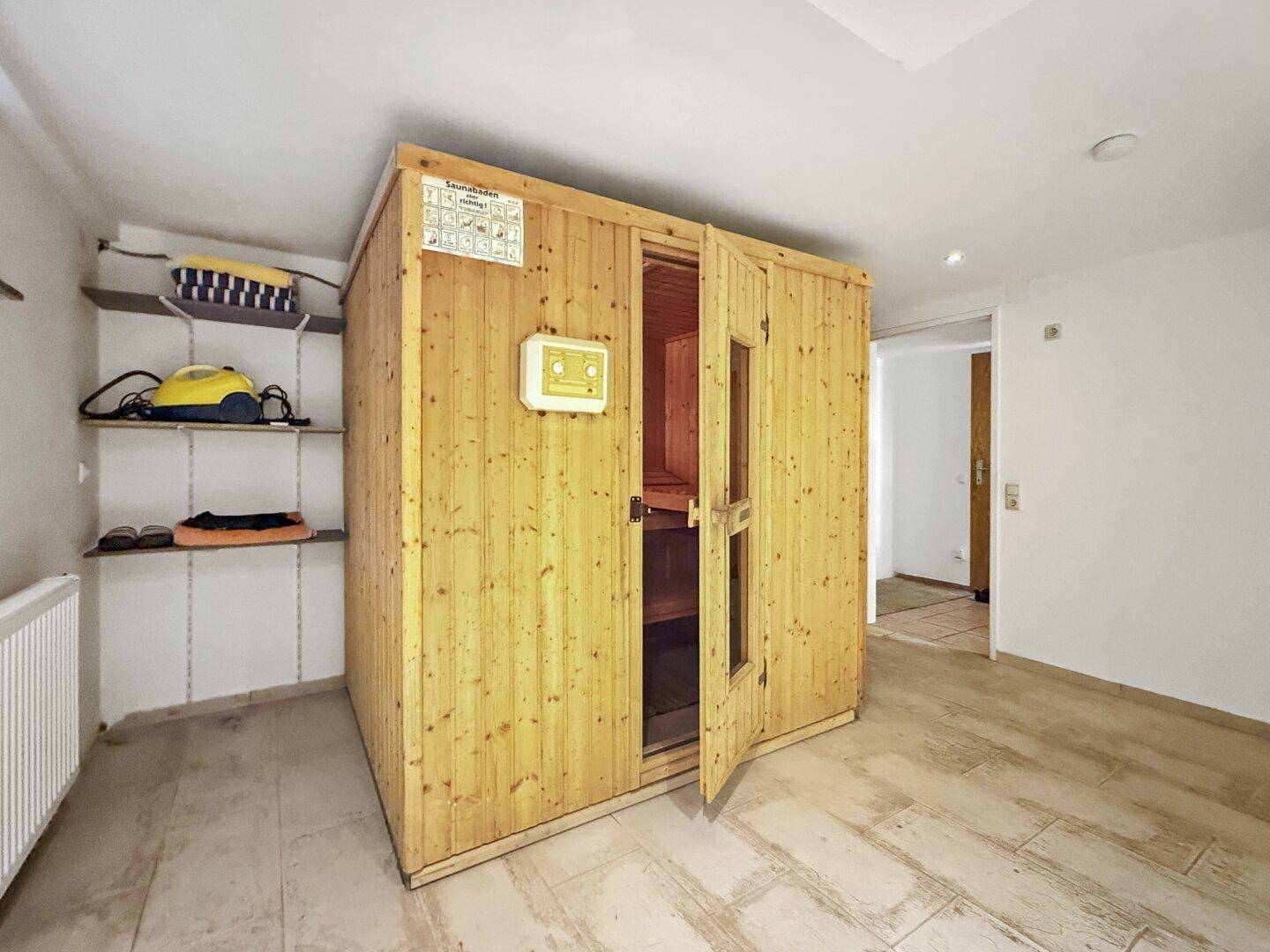 Wellnessbereich im Untergeschoss mit einer Holzsauna und Regalen für Lagerung.