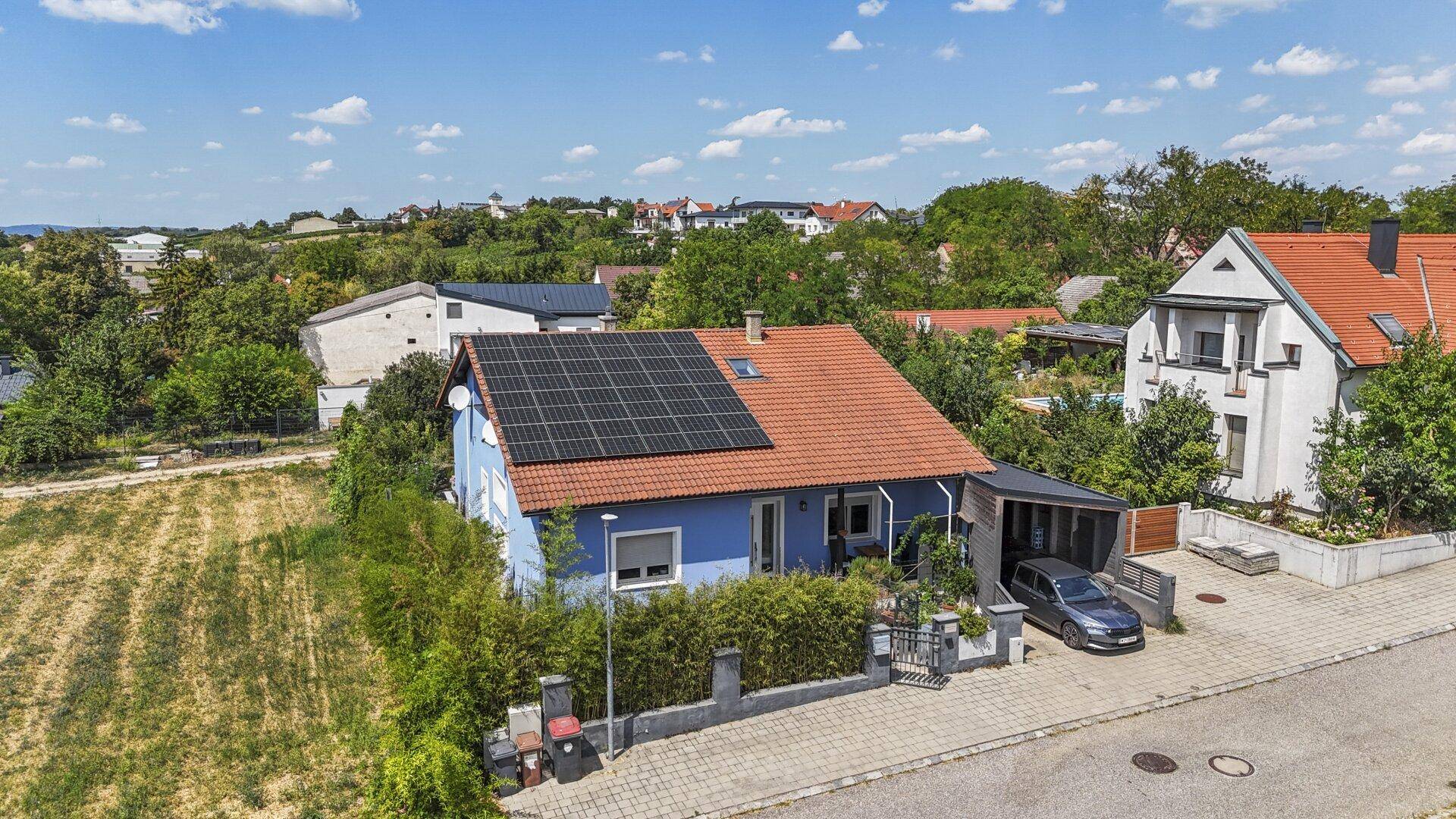 Luftaufnahme des Hauses mit Solaranlage und Carport, eingebettet in die grüne Umgebung.