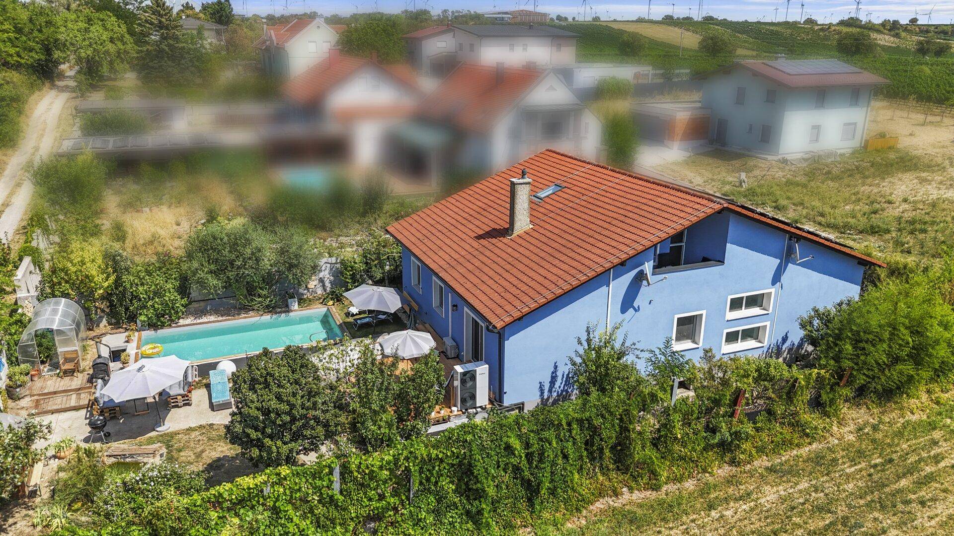Luftaufnahme des Hauses mit Pool, Gewächshaus und der weiten Landschaft im Hintergrund.