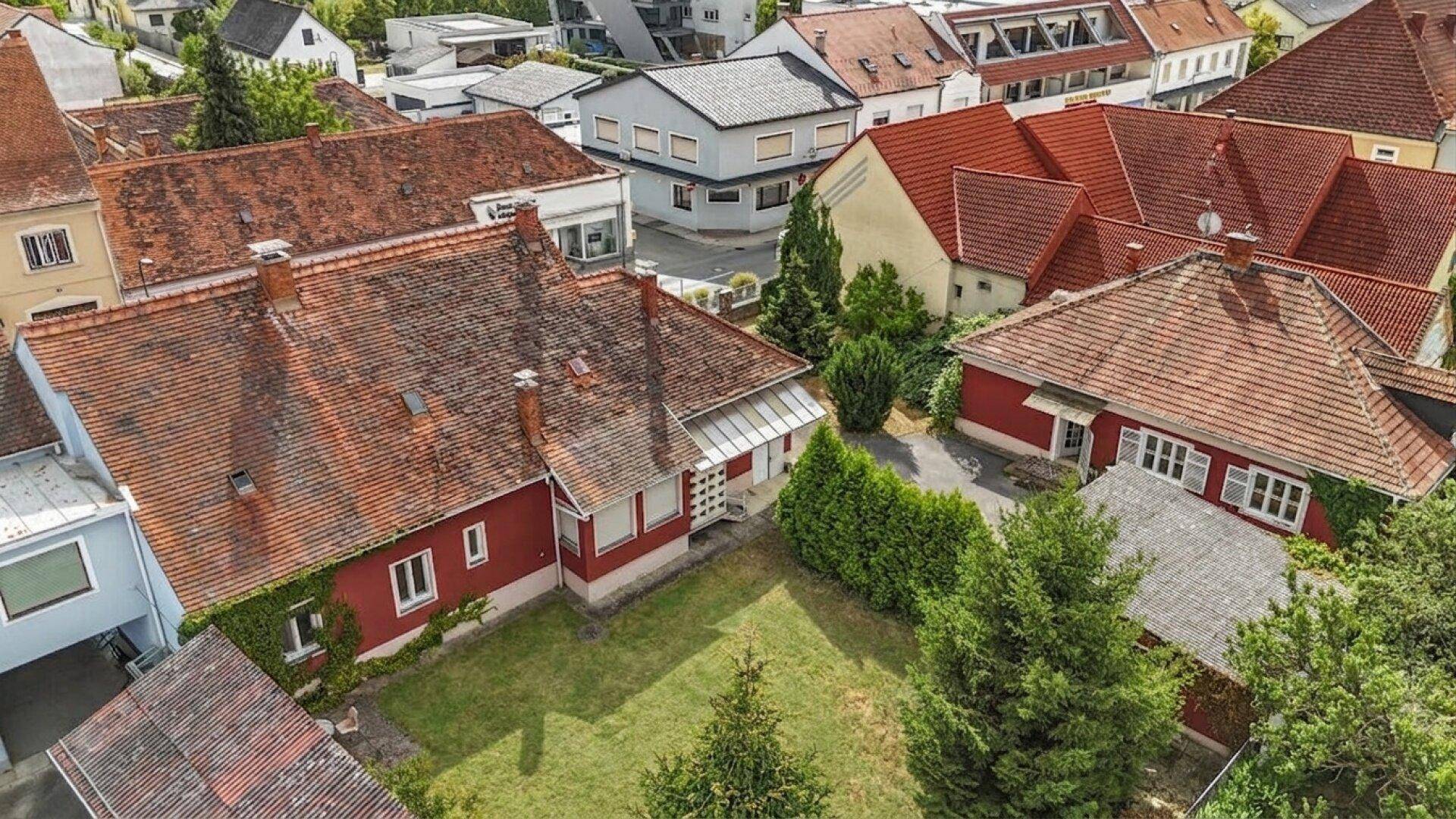 Vogelperspektive des roten Hauses mit Garten und umliegenden Wohnhäusern in ländlicher Umgebung.