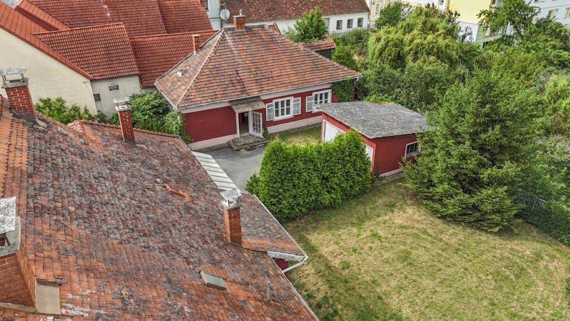 Luftaufnahme des roten Hauses von hinten mit großem Garten und einem kleinen Nebengebäude.