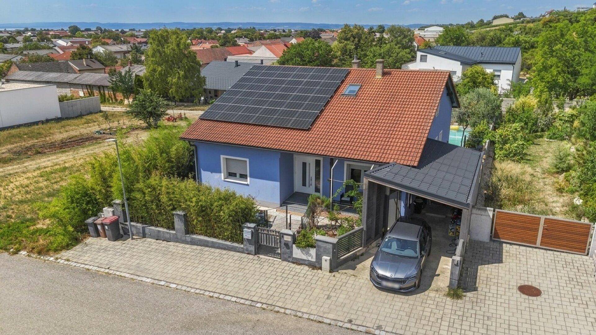 Luftaufnahme des Hauses mit Solaranlage auf dem Dach, Carport und der umliegenden Wohngegend.