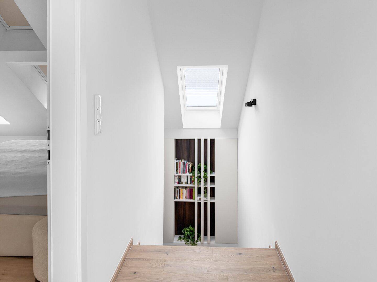 Heller Flur mit Dachfenster und integriertem Bücherregal im Dachgeschoss.