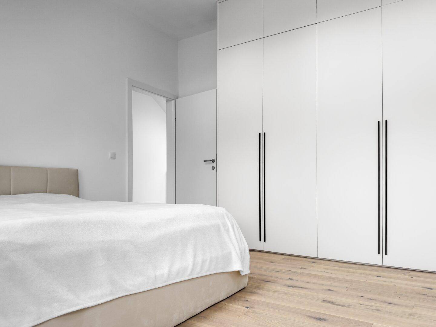 Helles Schlafzimmer mit modernem Einbauschrank und Holzboden.