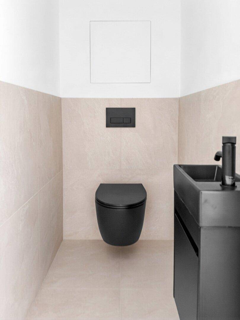Stilvolles Gäste-WC mit schwarzer Wandtoilette, passendem Waschbecken und hellen Fliesen.