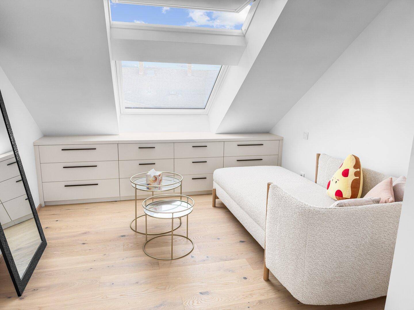 Gemütliches Zimmer unter der Dachschräge mit großem Dachfenster, Tagesbett und Einbauschränken.