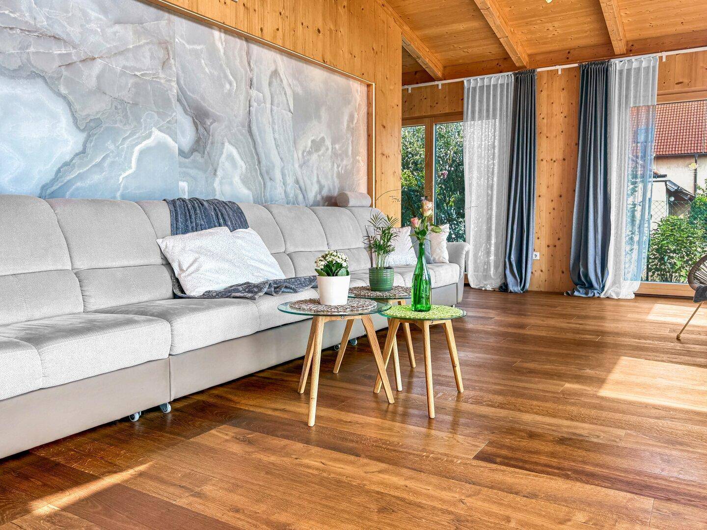 Geräumiges Wohnzimmer mit großem Sofa, Holzboden und einer stilvollen beleuchteten Wandverkleidung.