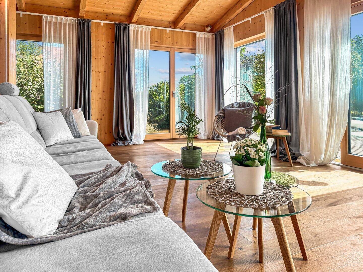 Lichtdurchflutetes Wohnzimmer mit gemütlichem Sofa, Holzboden und Zugang zu den Außenbereichen.
