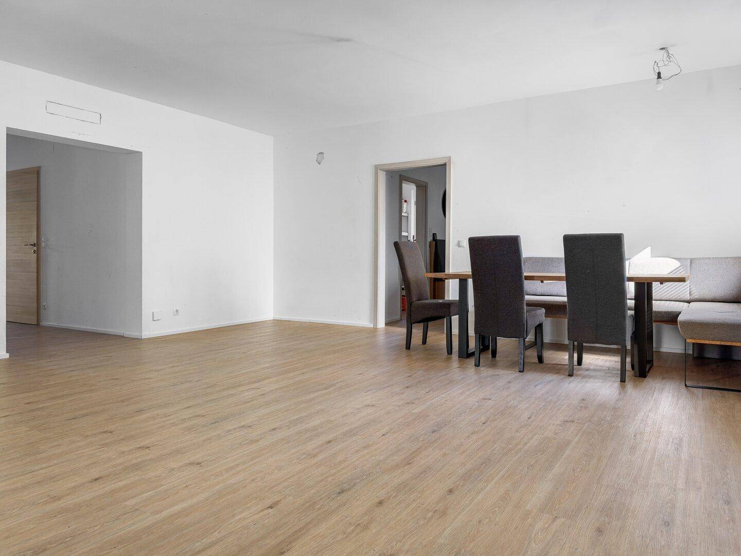 Geräumiger Essbereich mit hellem Laminatboden und weißen Wänden, bereit zur individuellen Gestaltung.