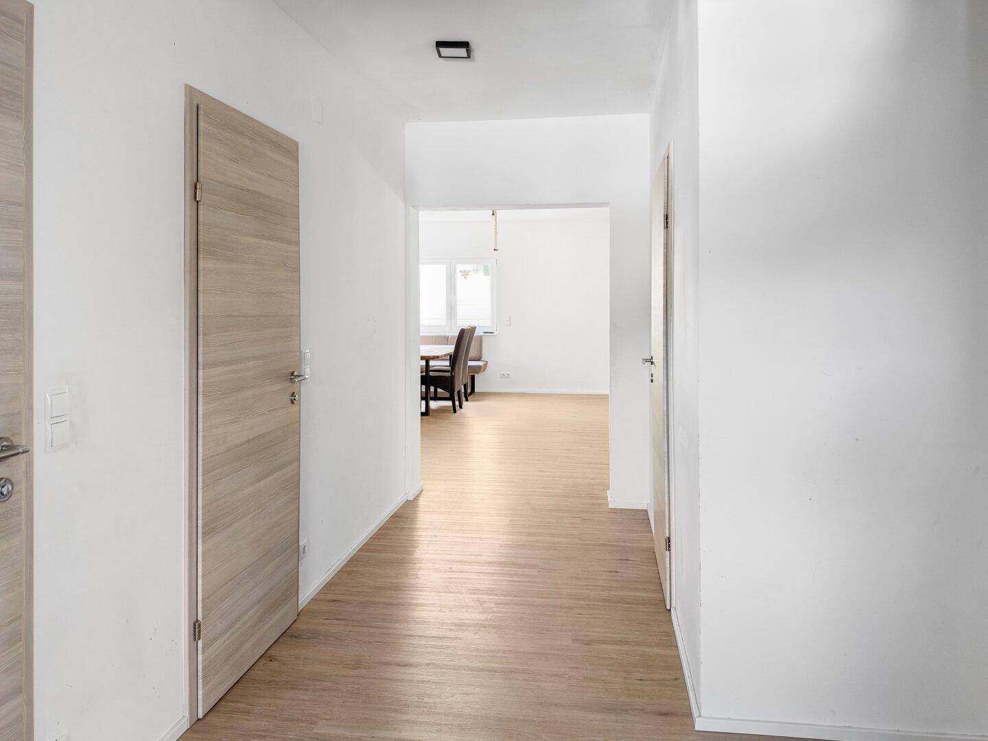 Heller Flur mit Laminatboden und modernen Holztüren, der zu den verschiedenen Räumen führt.