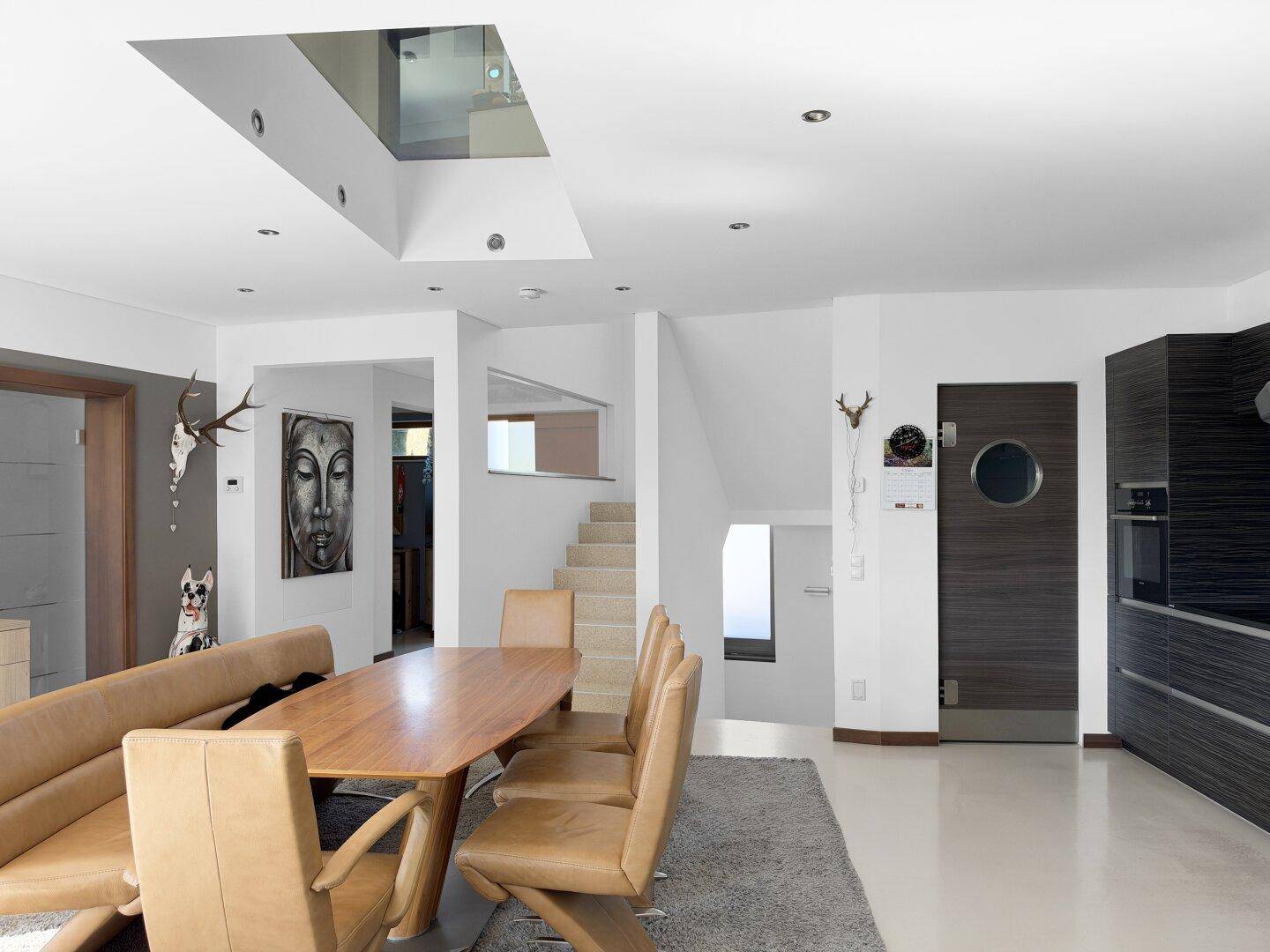 Geräumiger Essbereich mit Holztisch und moderner Küche, verbunden mit dem Treppenhaus und Oberlicht.