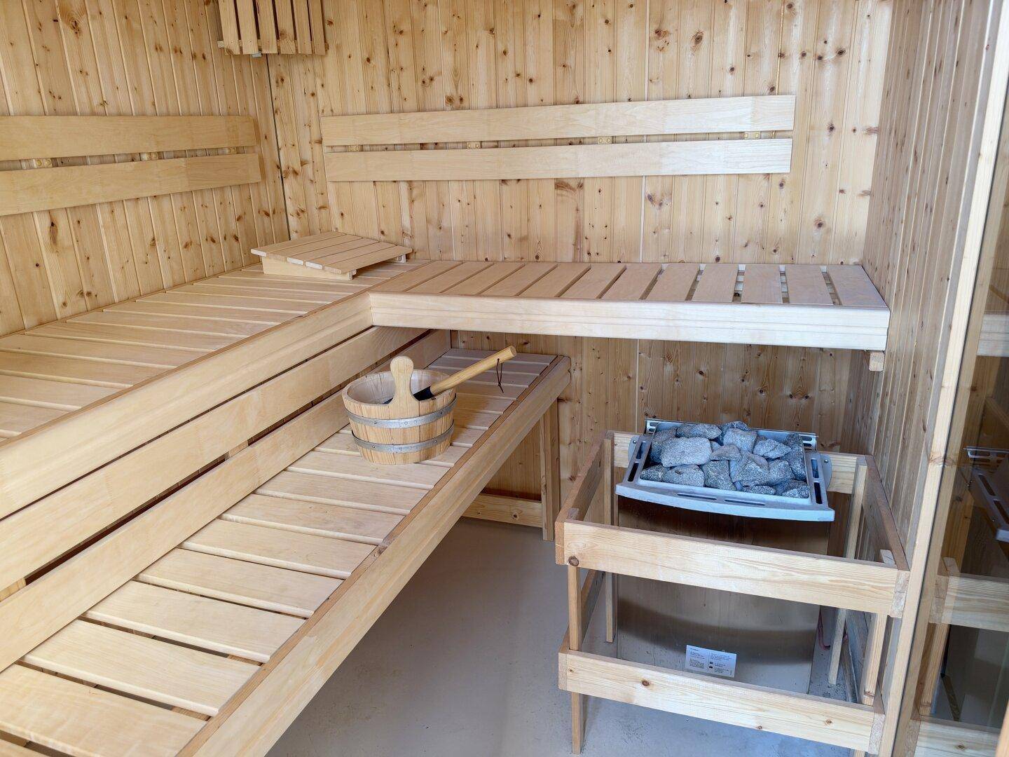Helle Holzsauna mit Bänken und Saunaofen, bereit zur Entspannung.