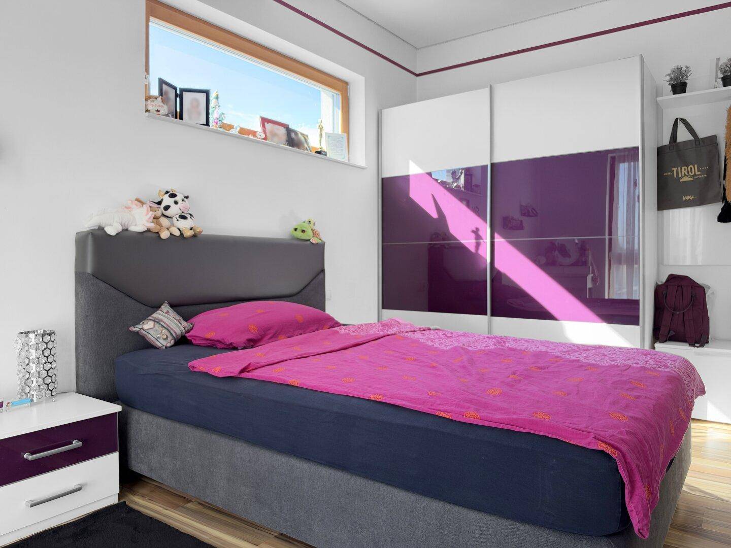 Modernes Schlafzimmer mit Bett, Kleiderschrank und Fenster, hell und funktional eingerichtet.