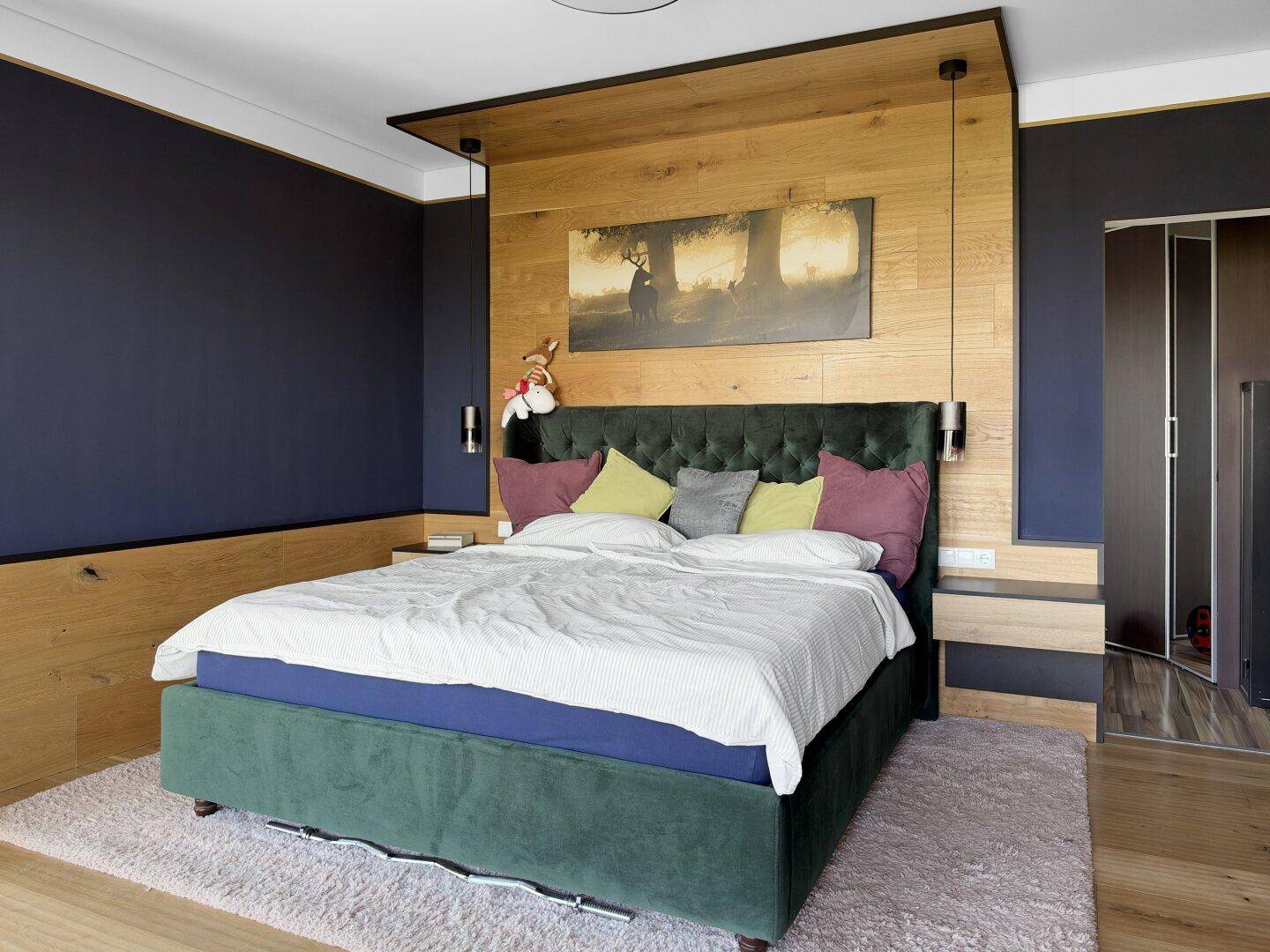 Gemütliches Schlafzimmer mit großem Bett, Holzakzenten und dunkelblauen Wänden.