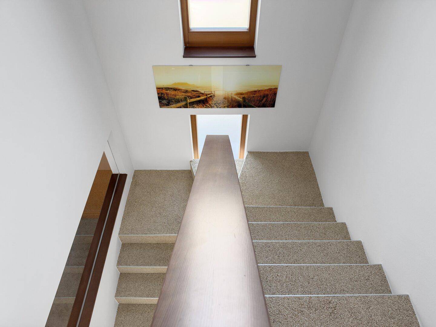Heller Treppenaufgang mit Holzgeländer und Oberlicht, das den Bereich erhellt.