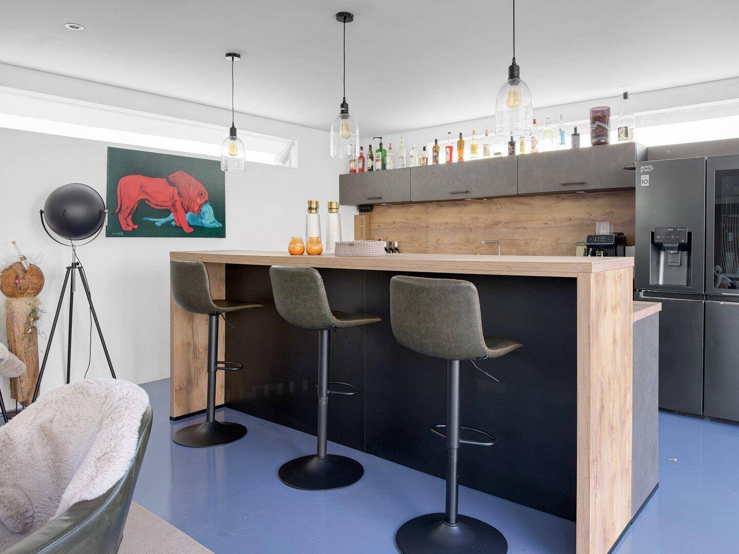 Moderne Bar mit Holztresen, Barhockern und integriertem Kühlschrank in offenem Wohnbereich.