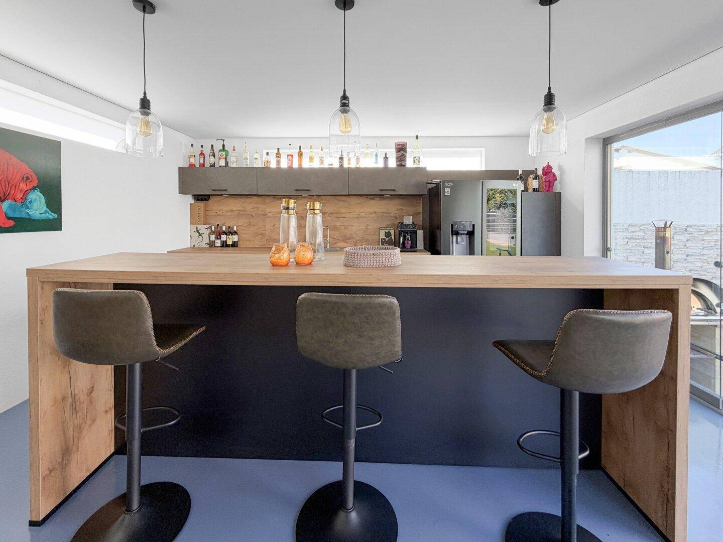 Stilvolle Hausbar mit dunklen Schränken, Holztheke und modernen Pendelleuchten.