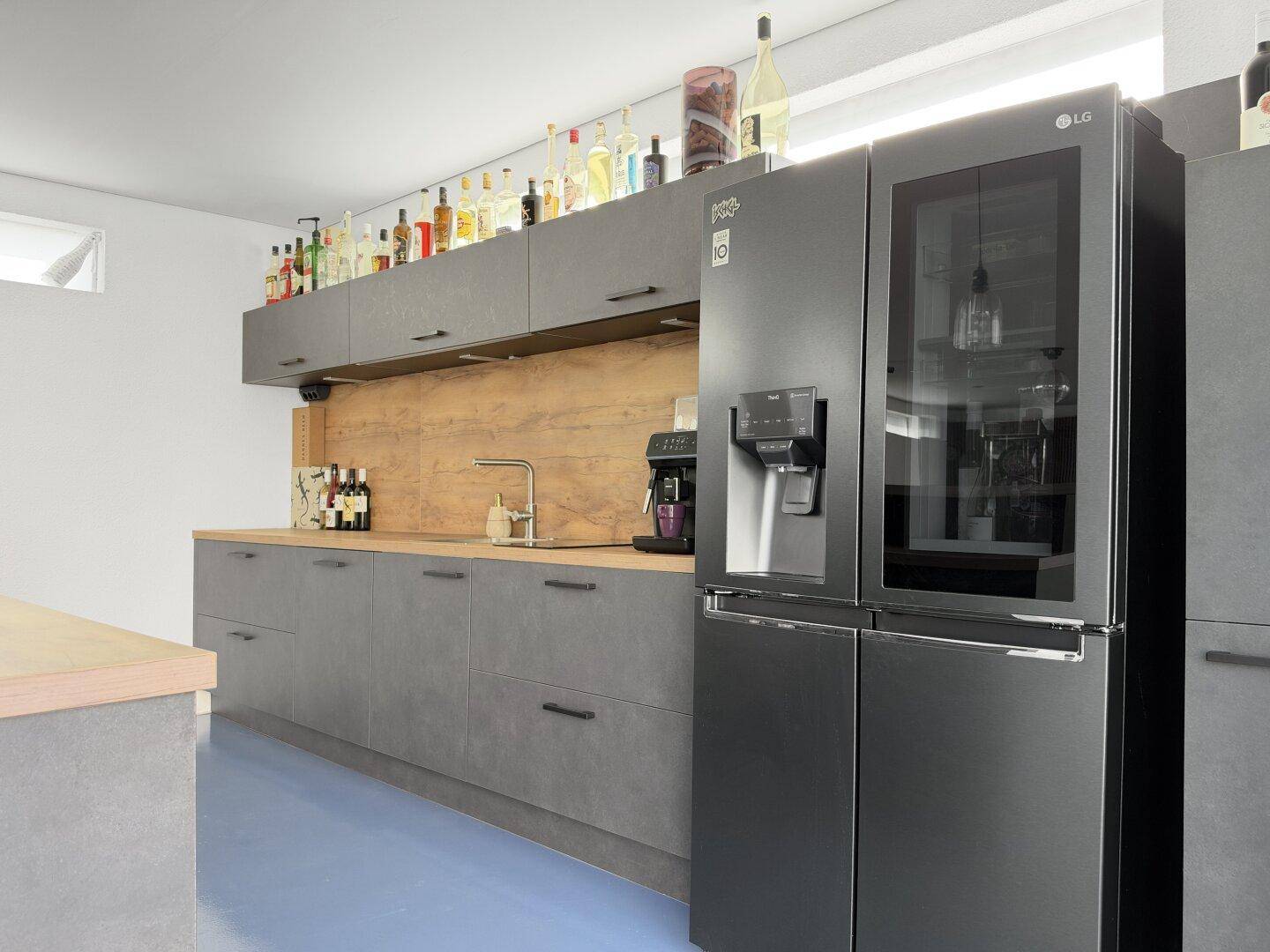 Hochwertige Küchenzeile mit dunklen Schränken, integriertem Kühlschrank und Kaffeemaschine.