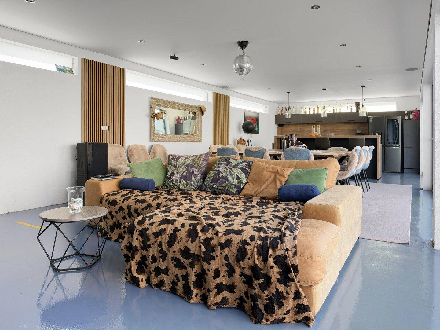 Offener Wohnbereich mit bequemer Couch, Blick auf den Essbereich und die Hausbar.