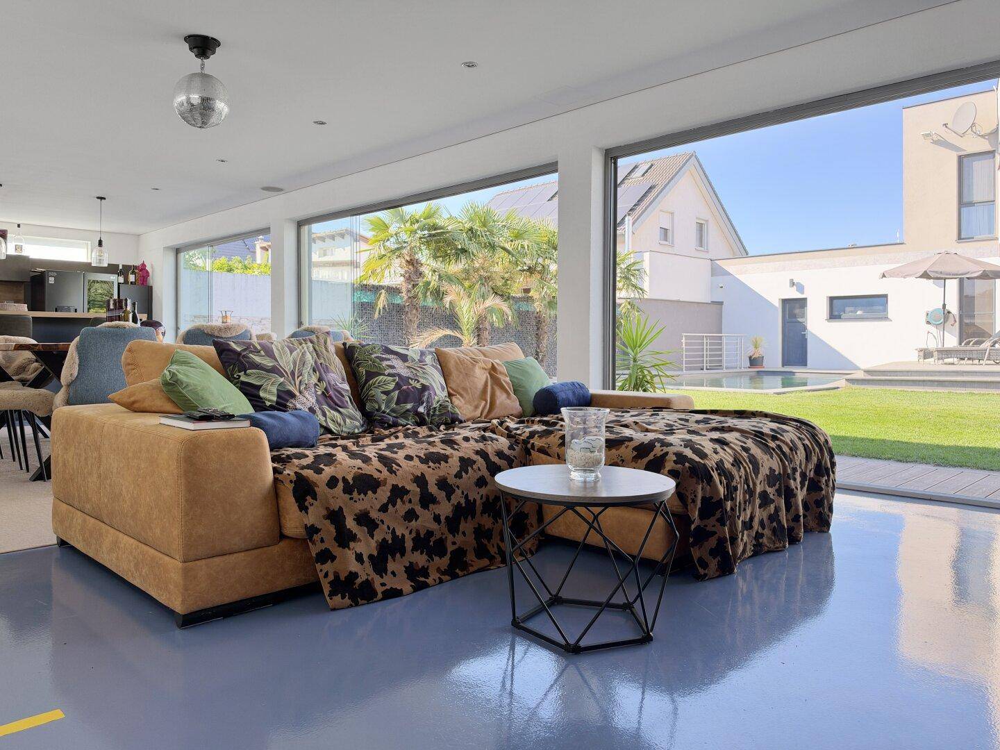 Gemütliches Wohnzimmer mit großem Ecksofa, modernen Möbeln und viel Tageslicht durch Panoramafenster.