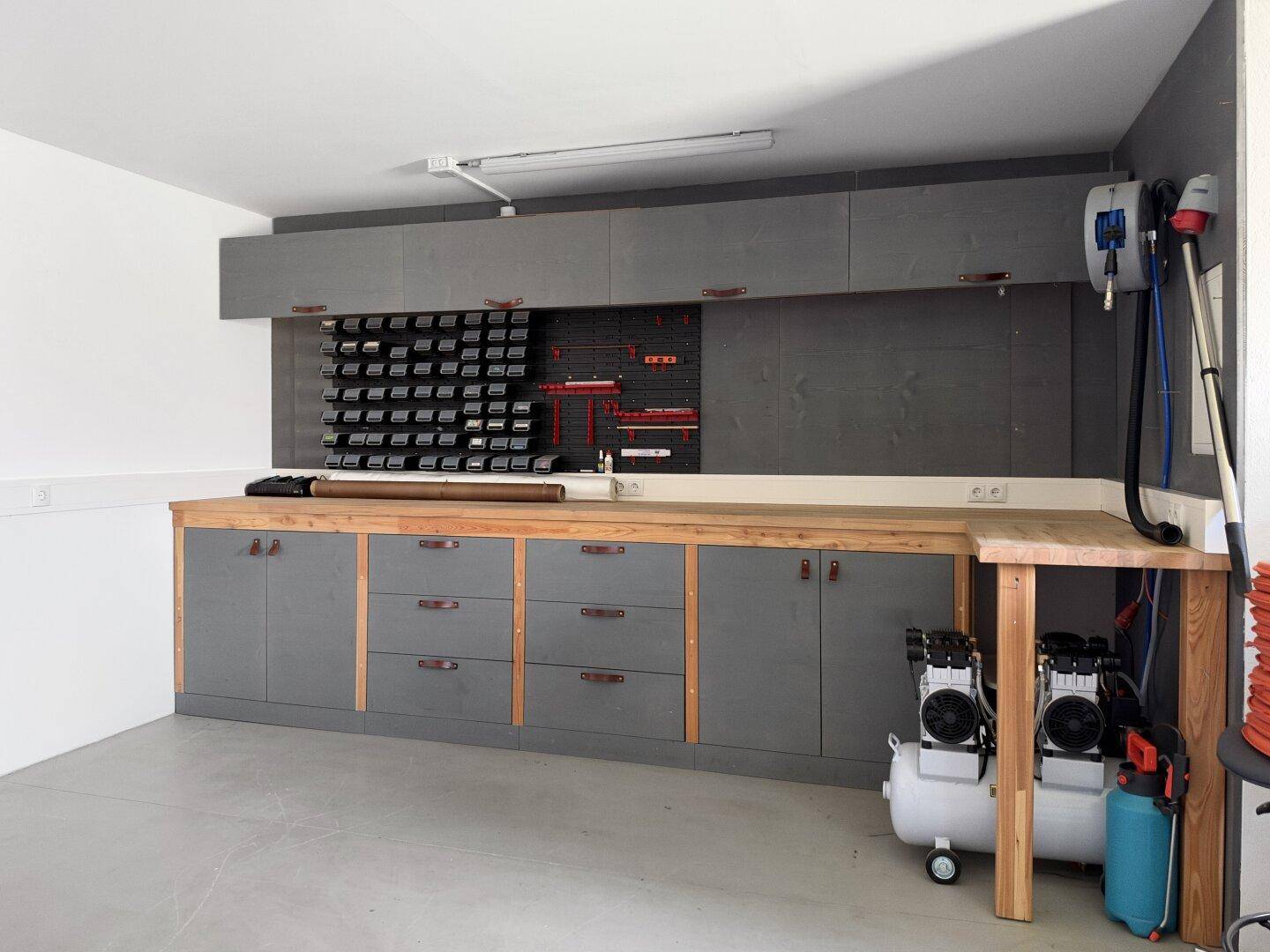 Gut ausgestattete Werkstatt in der Garage mit Arbeitsplatte und vielen Aufbewahrungsmöglichkeiten.