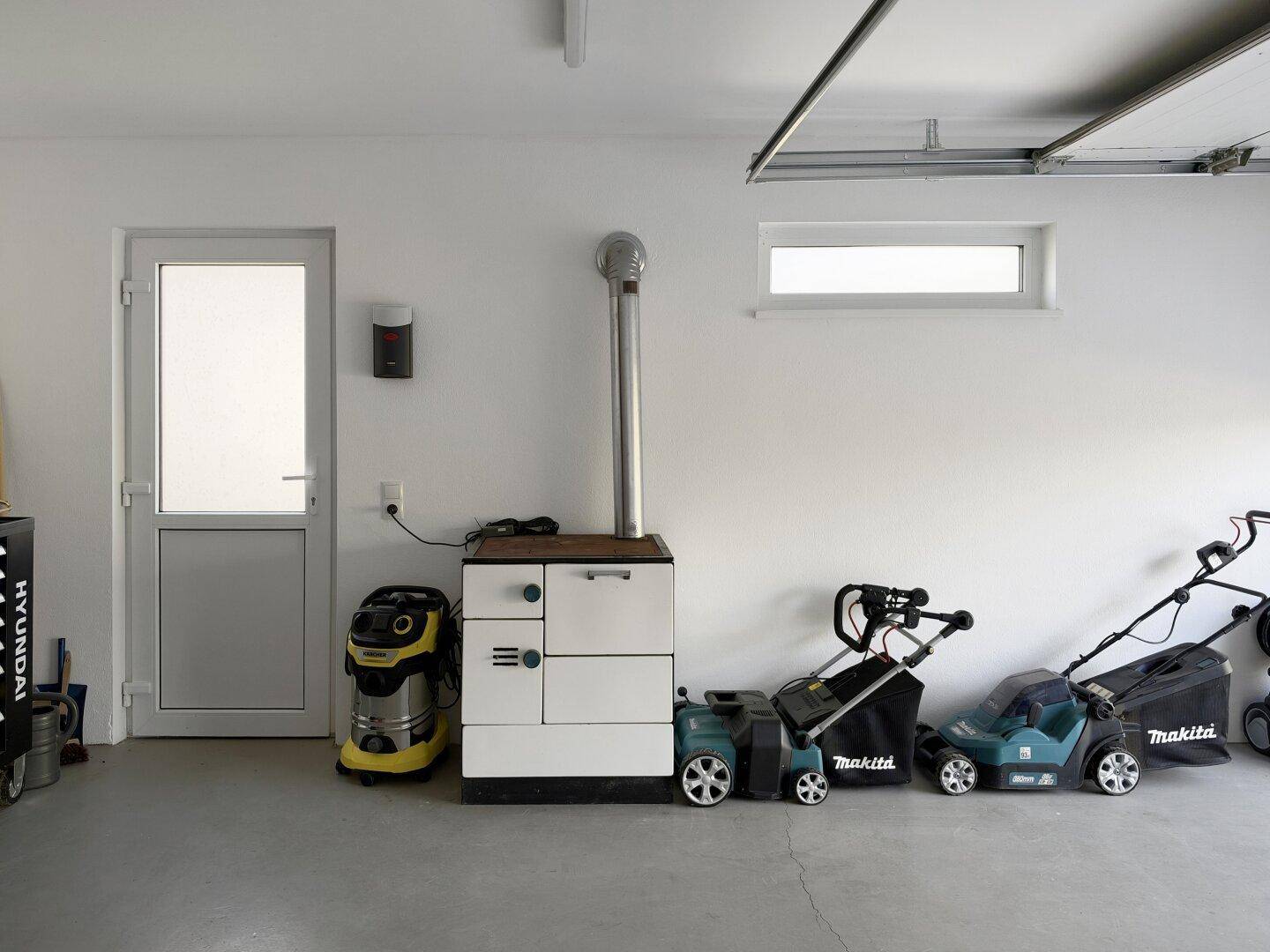 Garage mit Gartengeräten, einem Ofen und einem Fenster für Tageslicht.
