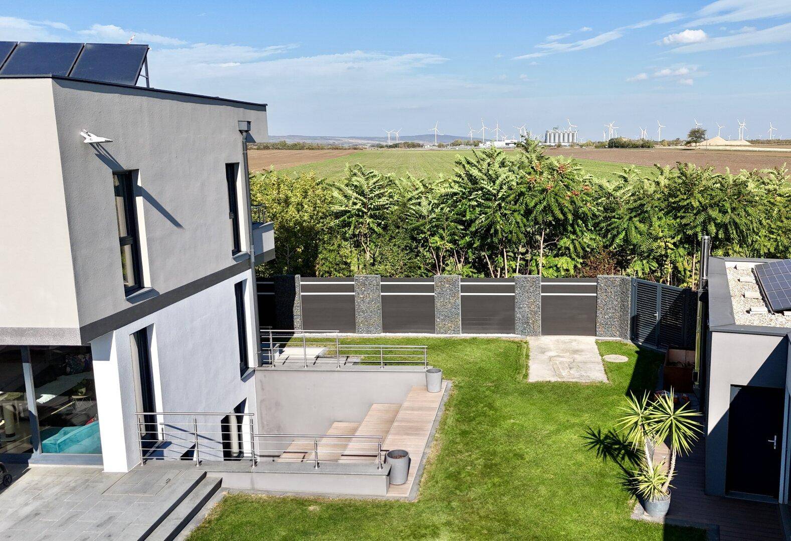 Gartenbereich mit Rasen, Treppenabgang und Blick auf die umliegende Landschaft.