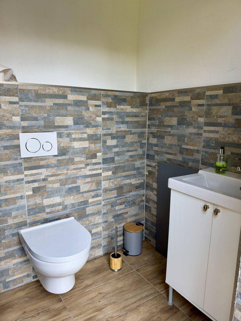 Modernes Gäste-WC mit Wand-WC, Waschbecken und gemusterten Fliesen.