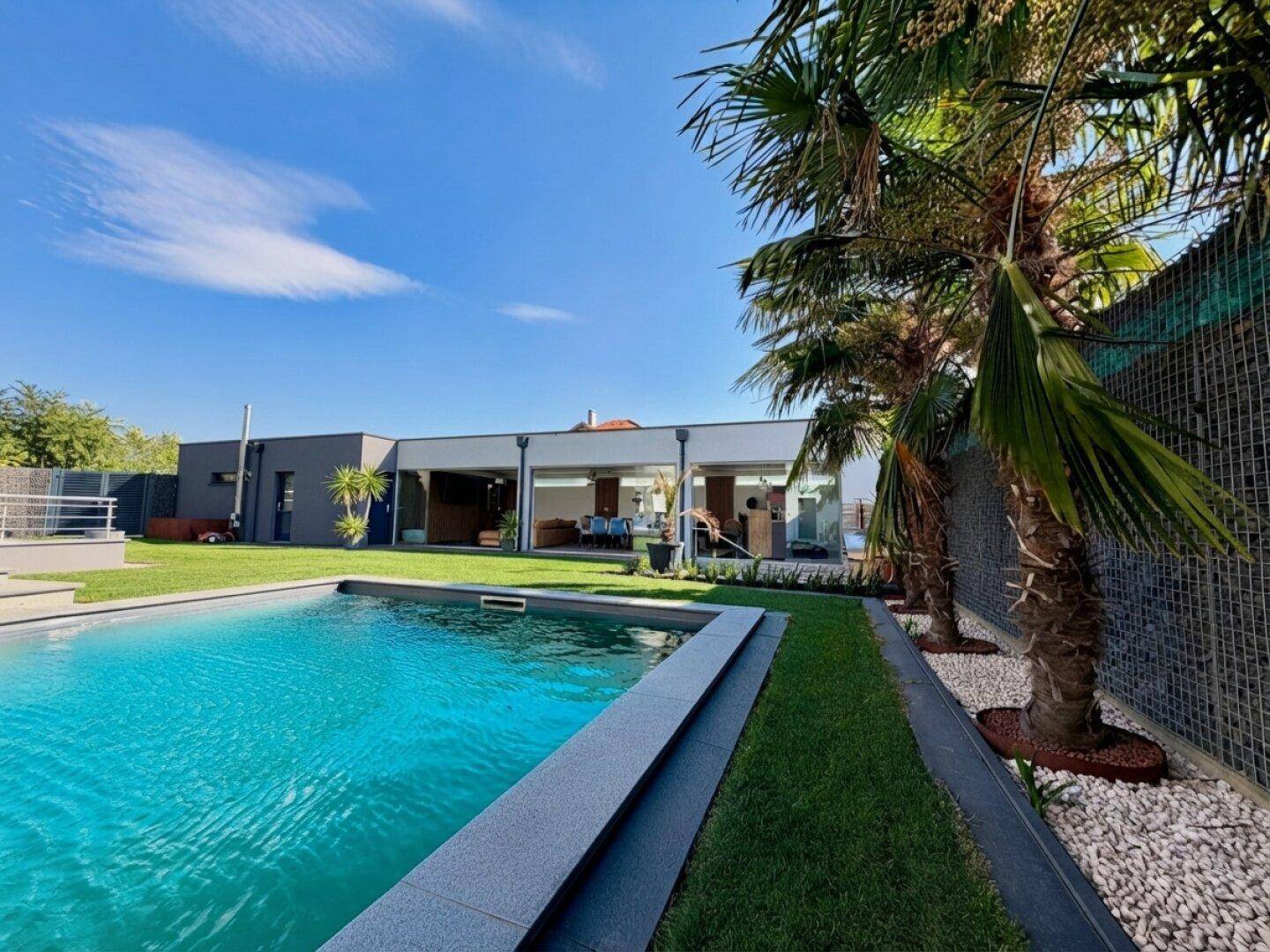 Weitläufiger Gartenbereich mit Swimmingpool und Blick auf den offenen Wohnbereich des Hauses.