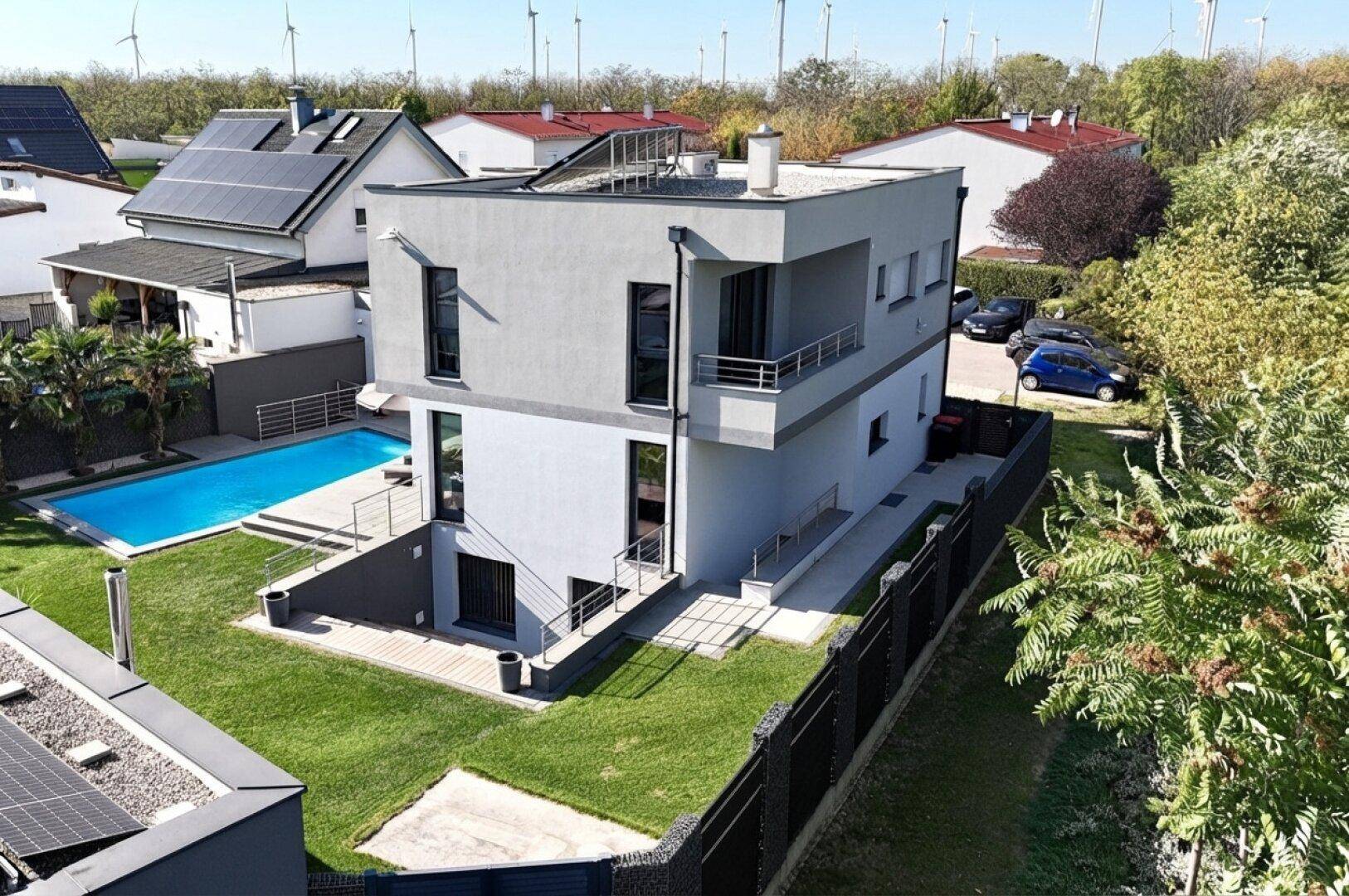 Vogelperspektive des modernen Hauses mit Pool, Garten und Blick auf die umliegende Bebauung.
