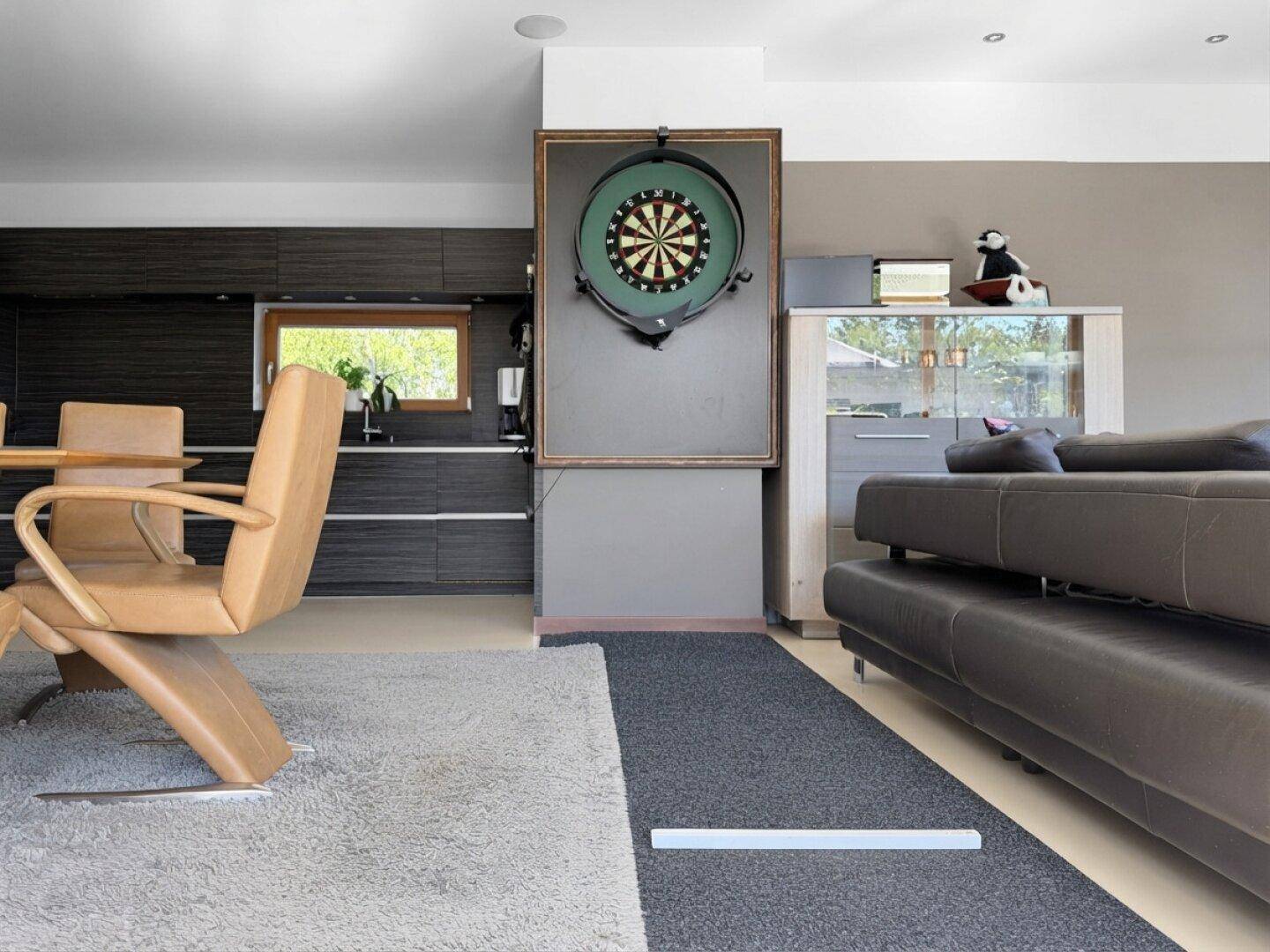 Gemütlicher Wohnbereich mit Sofa und Dartscheibe, angrenzend an die moderne Küche.