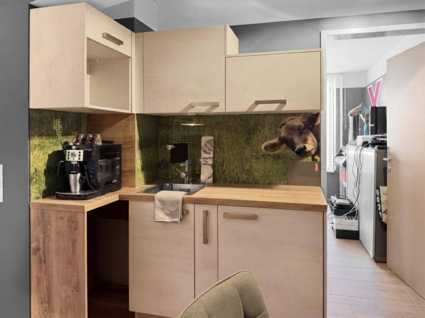 Kompakte Küchenzeile mit hellen Holzschränken, Spüle und Kaffeemaschine, funktional und platzsparend.