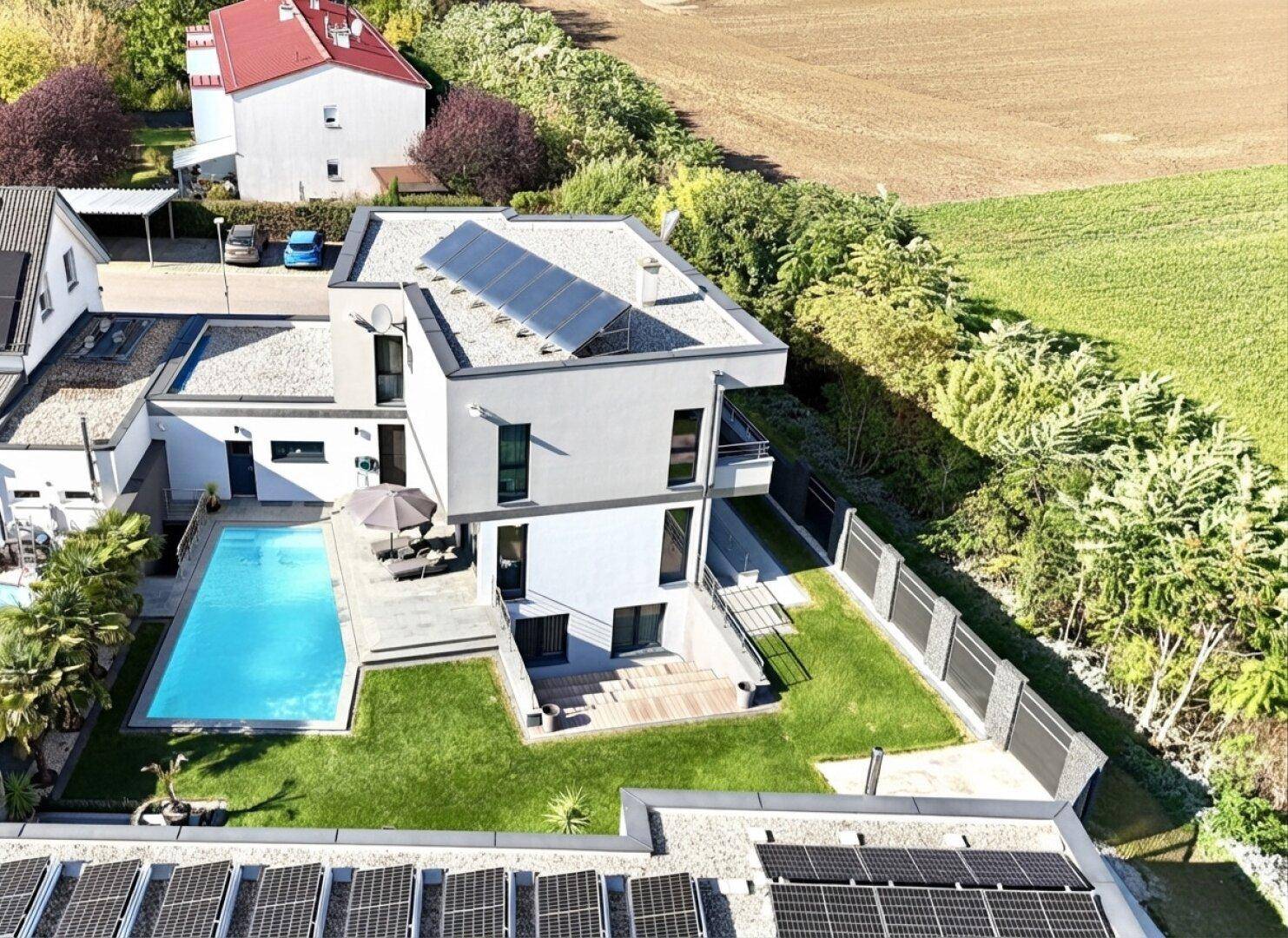 Weitläufige Gartenanlage mit Swimmingpool, Liegewiese und moderner Architektur.