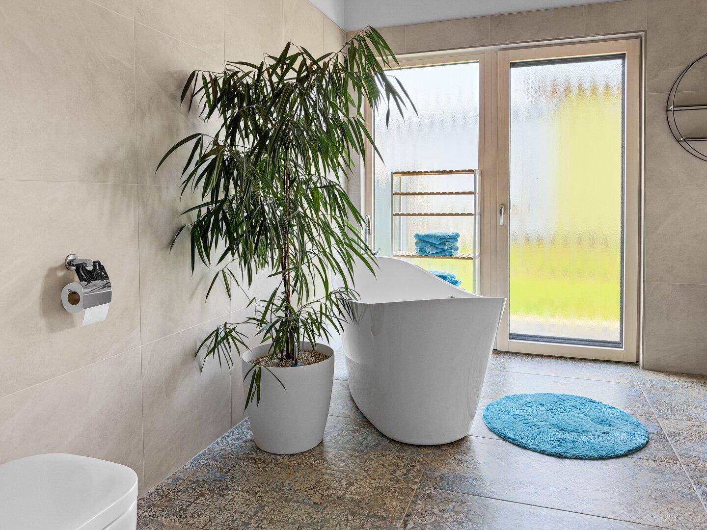 Modernes Badezimmer mit freistehender Badewanne, großen Fliesen und Fenster.