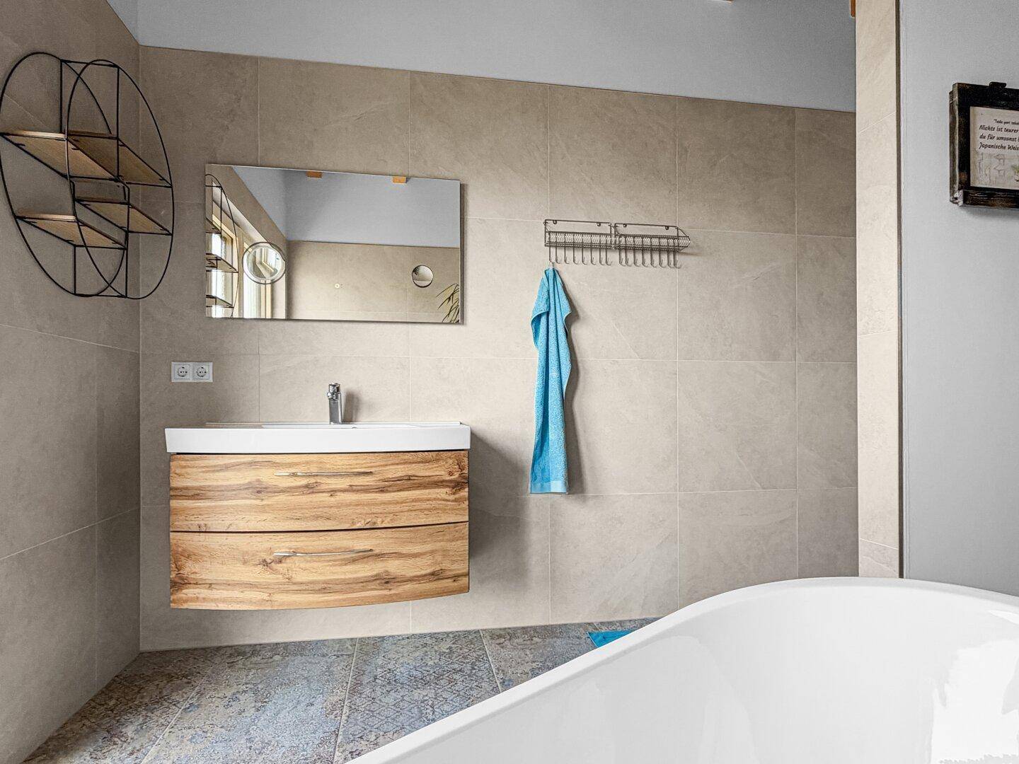 Modernes Badezimmer mit Waschtisch, Spiegel und freistehender Badewanne im Hintergrund.