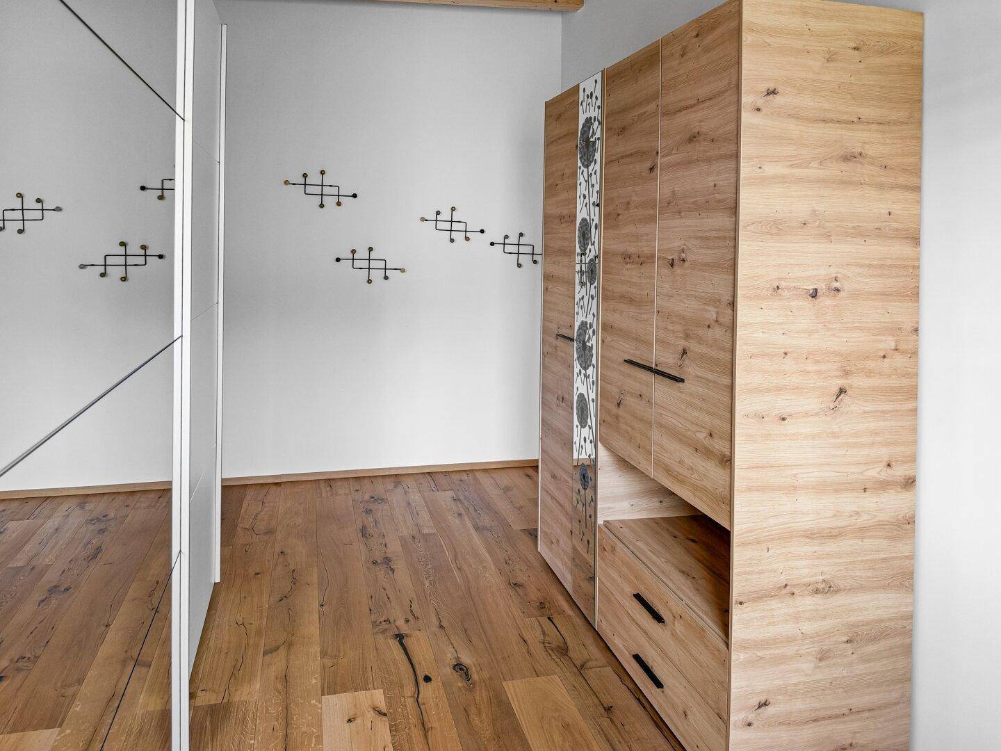 Schlafzimmer mit Holzboden und großem Kleiderschrank, der viel Stauraum bietet.
