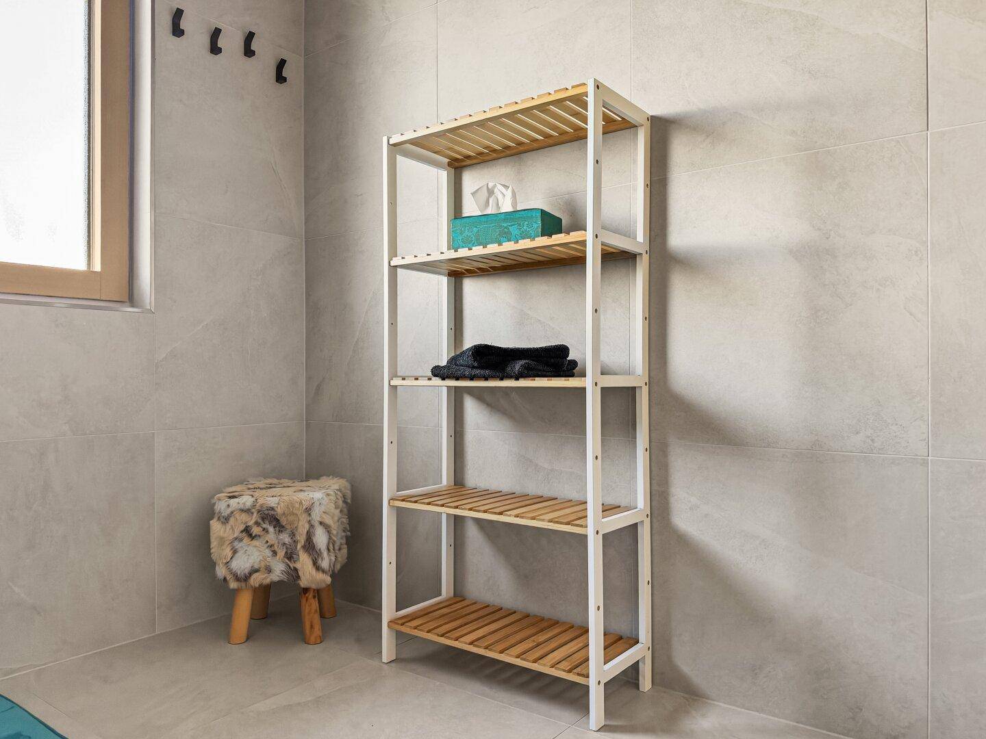 Badezimmer mit Holzregal, Hocker und Fenster, das natürliches Licht hereinlässt.