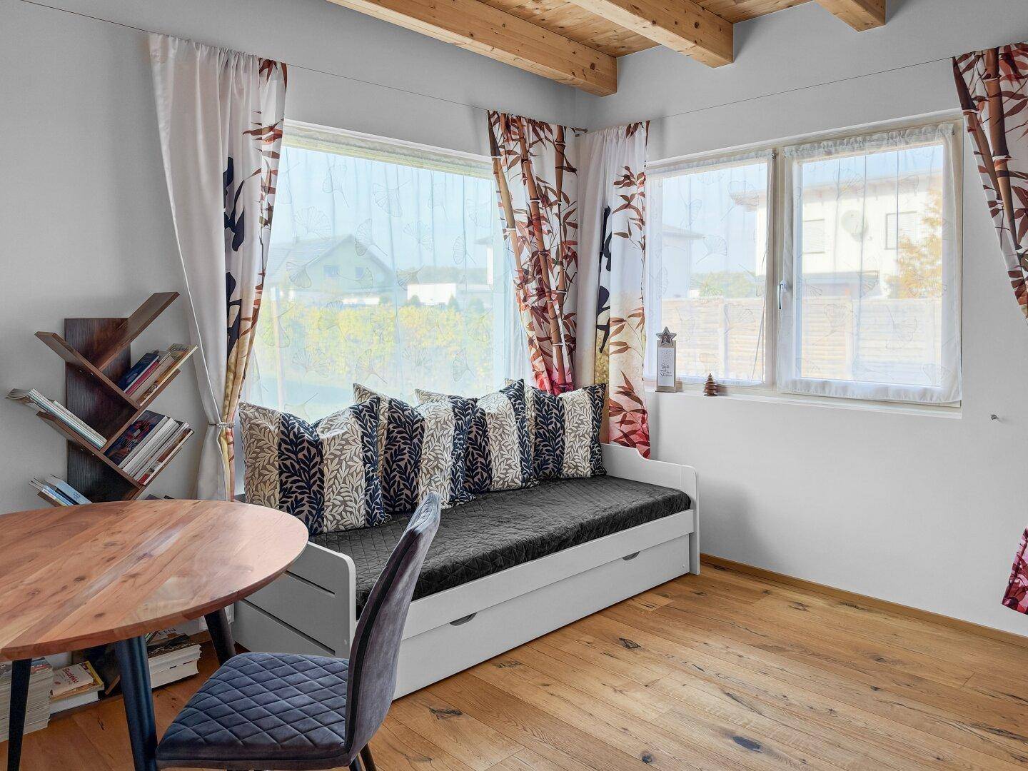 Helles Zimmer mit Holzbalkendecke, Parkettboden und Tagesbett, ideal als Gäste- oder Wohnbereich.