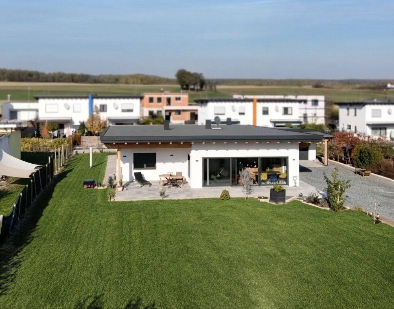 Modernes Einfamilienhaus mit Flachdach und großem Garten in ländlicher Umgebung.
