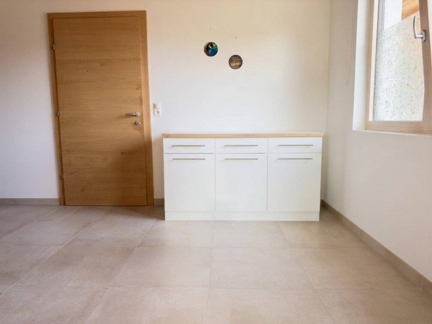 Heller Eingangsbereich mit Fliesenboden, Holztür und praktischem Sideboard.