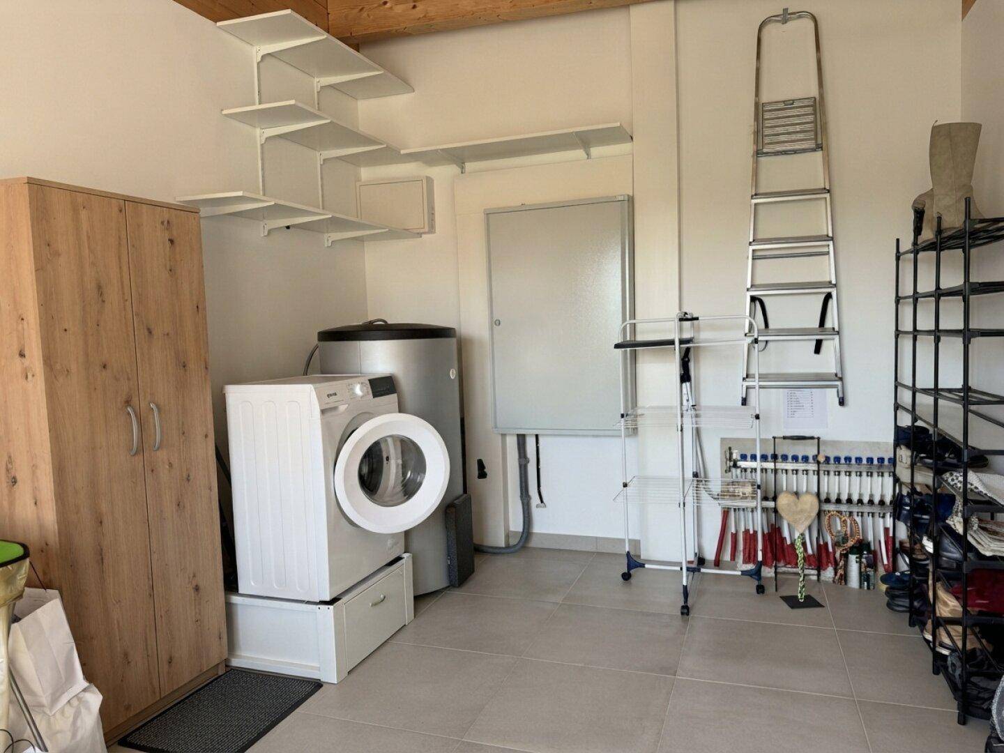Funktionaler Hauswirtschaftsraum mit Waschmaschine, Warmwasserspeicher und praktischen Regalen.