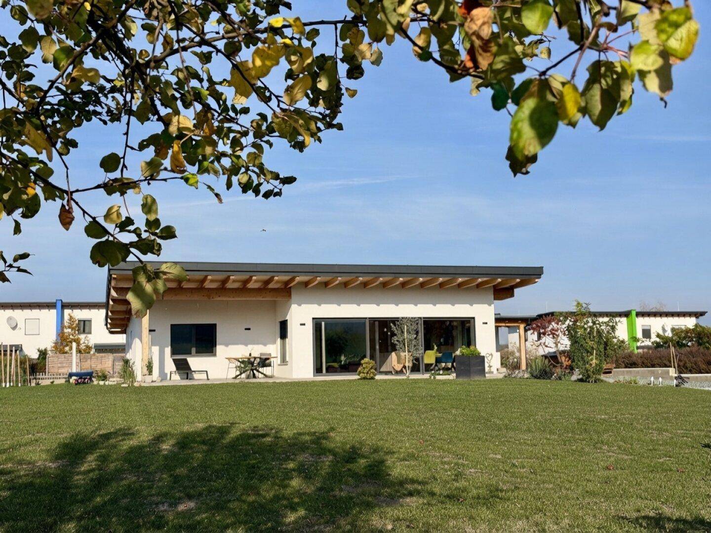 Modernes Einfamilienhaus mit Flachdach, großer Rasenfläche und sonniger Ausrichtung.