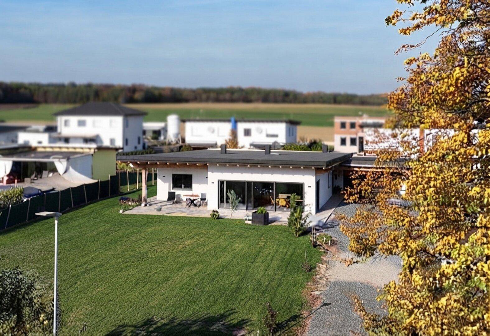 Luftaufnahme eines modernen Einfamilienhauses mit großem Garten in ländlicher Umgebung.