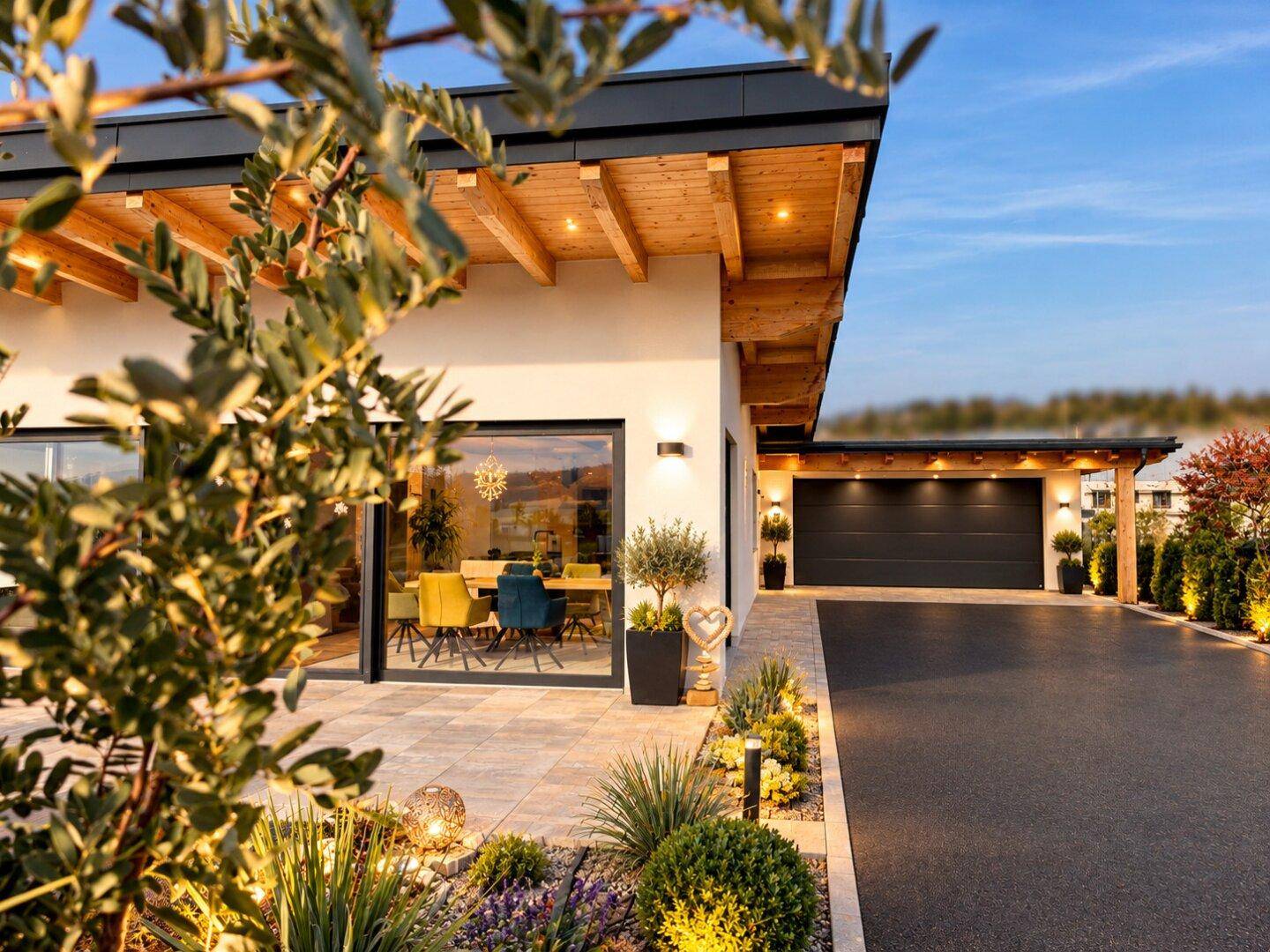 Seitenansicht der modernen Villa mit Einfahrt, Carport und Blick in den hellen Essbereich.